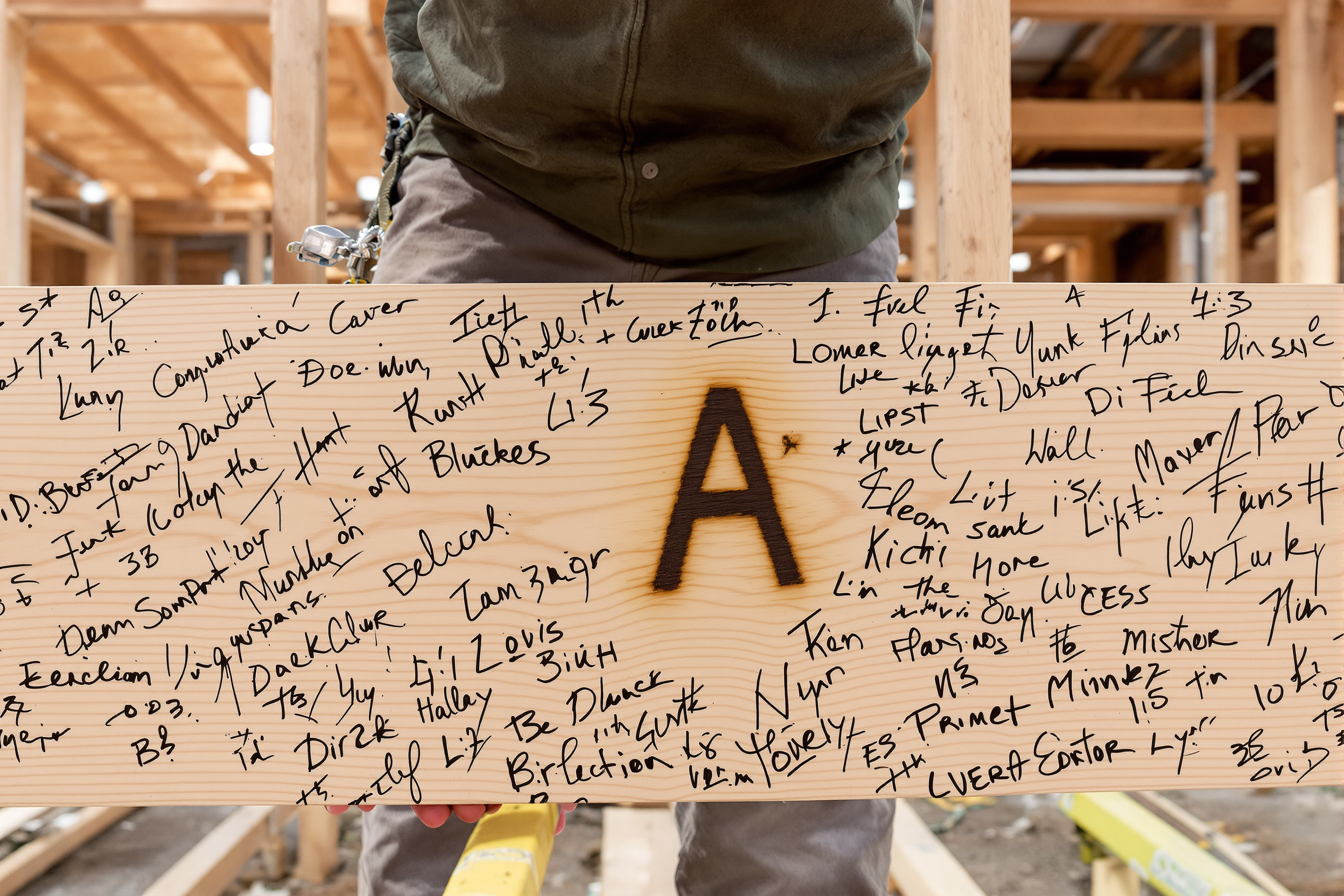 The Arcadia Signature — a branding-iron mark burned into a structural beam, family signatures beside it